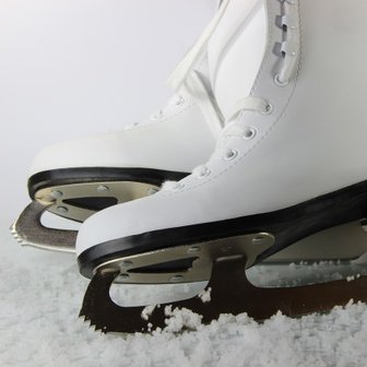 Nahaufnahme von weißen Schlittschuhen mit glänzenden Kufen, die auf frischem Schnee platziert sind.