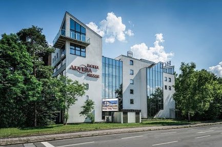 Ein modernes Gebäude mit großen Fenstern und einer auffälligen Fassade, umgeben von Bäumen und einem klaren Himmel.