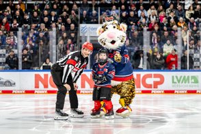 Auf dem Eis posieren ein Schiedsrichter, ein kleiner Eishockeyspieler und ein fröhliches Tiger-Maskottchen zusammen.