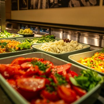 Einladende Präsentation von frischen Zutaten, darunter knackige Salate und farbenfrohes Gemüse, bereit für die Gäste.