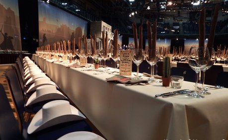 Lange Tafel mit eleganten Gläsern und rustikalen Dekorationen, die eine einladende Atmosphäre für eine Gala schafft.