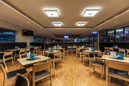 Ein modernes Restaurant mit Holzfußboden, Tischen und Stühlen, den den VIP-Bereich der Arena gerecht werden.