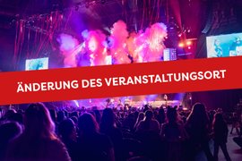 Eine lebhafte Konzertszene mit bunten Lichtern und Nebel, während das Publikum gespannt zuschaut.