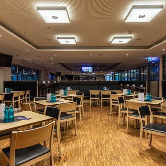 Ein modernes Restaurant mit Holzfußboden, Tischen und Stühlen, den den VIP-Bereich der Arena gerecht werden.