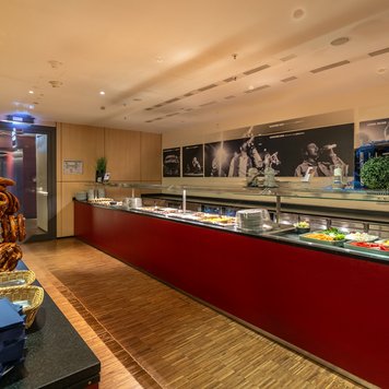 Der Buffetbereich bietet eine Vielzahl von Speisen, darunter bunte Salate und frisch gebackene Brezeln, in modernem Ambiente.