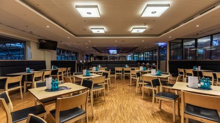 Ein modernes Restaurant mit Holzfußboden, Tischen und Stühlen, den den VIP-Bereich der Arena gerecht werden.