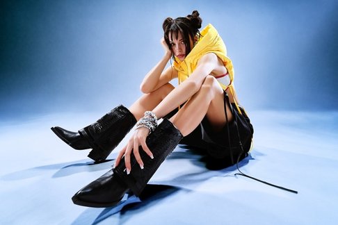 Nina Chuba auf den Boden sitzend mit blauen Hintergrund