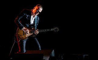 Joe Bonamassa auf der Bühne Gitarre spielend mit dunklem Hintergrund
