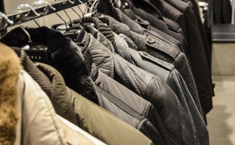 Eine Reihe von Jacken hängt ordentlich an einem Kleiderständer, jede in verschiedenen Grautönen und Materialien.