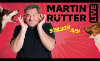 Martin Rütter hält sich die Ohren zu, während links und rechts von ihm je ein Hund bellt