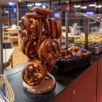Der Brezelständer ist reichlich gefüllt mit großen, goldbraunen Brezeln, umgeben von einem eleganten Restaurantambiente.