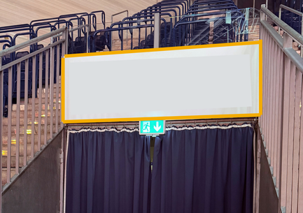 Ein dunkler Vorhang verdeckt einen Bereich in einer Sportarena, mit einer Notausgangsbeleuchtung darunter.